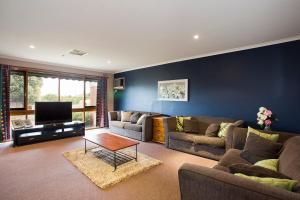 uma sala de estar com dois sofás e uma televisão em Geelong Holiday Home em Geelong