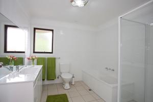 a white bathroom with a toilet and a shower at Geelong Holiday Home in Geelong