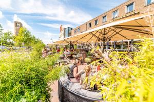 a group of people sitting at a restaurant with plants at Hotel Restaurant Grandcafé 't Voorhuys in Emmeloord