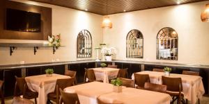 a dining room with tables and chairs and a tv at Vila Romana Park Hotel in Três Lagoas