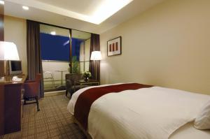 a hotel room with a bed and a desk and a window at Rembrandt Hotel Atsugi in Atsugi