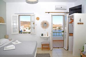 a white room with a bed and a balcony at NEFELI SUITES KYTHNOS in Loutrá