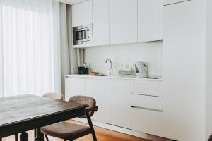 a kitchen with white cabinets and a table and chairs at 54 São Paulo - Exclusive Apartment Hotel in Lisbon