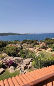 uma vista para um jardim com um banco e para o oceano em Casa Pedra Concada em Marinella