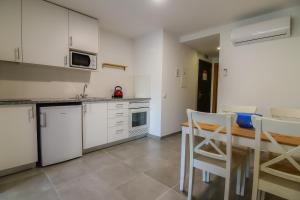a kitchen with white cabinets and a table and chairs at Bayside Salgados in Albufeira
