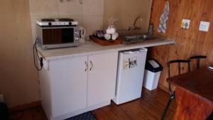 una pequeña cocina con microondas y fregadero en The Cottage Polokwane en Polokwane