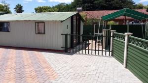 ein Gebäude mit einem Zaun und einem Spielplatz in der Unterkunft The Cottage Polokwane in Polokwane