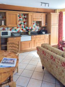 eine Küche mit Holzschränken, einem Tisch und einer Couch in der Unterkunft Val Rive - Degas Apartment in Dinan