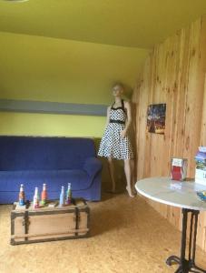 a woman standing in a living room with a blue couch at Chambres chez L’habitant in Couvin