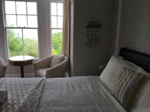 a bedroom with a bed and a chair and a window at Borthalan House in Carbis Bay