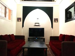a living room with two red couches and a tv at Apart- Groupe Marhaba in Marrakesh