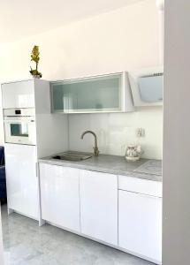 eine weiße Küche mit weißen Schränken und einem Waschbecken in der Unterkunft Apartament Międzyzdroje B42 in Misdroy
