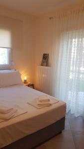 une chambre avec un lit avec des draps blancs et une fenêtre dans l'établissement Onar View Apartment, à Néa Péramos