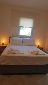 - un lit avec 2 serviettes et une fenêtre dans l'établissement Onar View Apartment, à Néa Péramos
