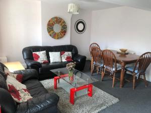 a living room with a black leather couch and a table at 4c Belmont Terrace in Buxton