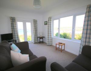 sala de estar con sofá y 2 ventanas en Gullsway September Tide, en Polzeath