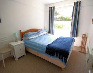1 dormitorio con 1 cama con manta azul y ventana en Gullsway Sandpiper, en Polzeath