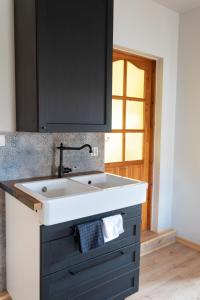 a kitchen with a white sink and a black cabinet at Nowe Kawkowo 28 in Jonkowo