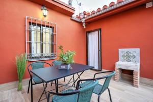una mesa y sillas en un patio con una pared de color naranja en Tina Home, en Granada