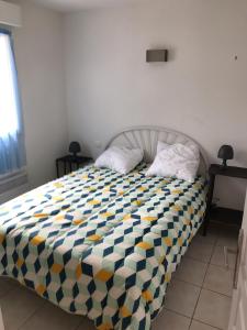 a bedroom with a bed with a checkered blanket on it at Maison bord de Lac de Pareloup in Salles-Curan