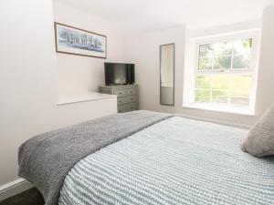 a white bedroom with a bed and a television at 3 Higher Lane in Macclesfield