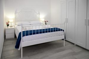 um quarto branco com uma cama branca e um cobertor azul em SalentosulMare em Marina di Lizzano