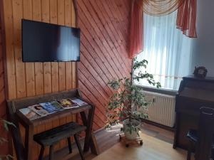 Ferienwohnung Weiß في أوي: غرفة بها تلفزيون على جدار مع طاولة