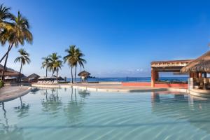 einen Pool neben einem Strand mit Palmen in der Unterkunft Holiday Inn Resort Ixtapa All-Inclusive, an IHG Hotel in Ixtapa