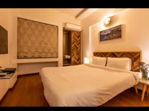 - une chambre avec un grand lit blanc et une fenêtre dans l'établissement Mizzle Exotica Lonavala, à Lonavala