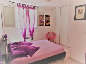 a bedroom with a bed with purple sheets and a chair at Maison De Village in Saint-Raphaël