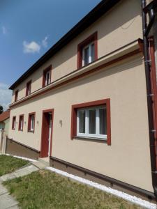 una casa con ventanas rojas en el lateral. en Ubytování Apartmány Ferenčíková, en Nové Hrady