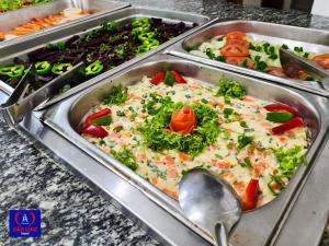 a buffet of vegetables in trays with a spoon at Hotel São Luiz in Aparecida