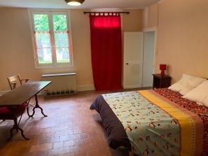 a bedroom with a bed and a table and a red curtain at Gîte proche Zoo Beauval 41 in Angé