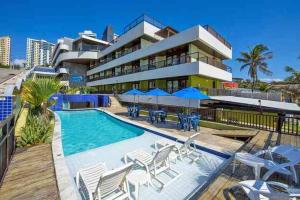 a resort with a swimming pool and chairs and a building at Flat pé na areia Ponta Negra Natal RN 09 in Natal