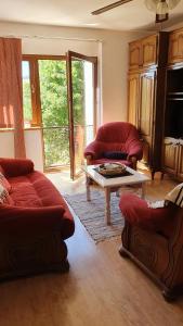 uma sala de estar com dois sofás vermelhos e uma mesa em Apartman CaCO3 - Potpuno opremljen stan u blizini Plitvičkih jezera em Korenica
