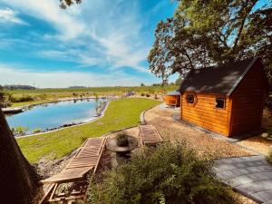 a small wooden cabin with a bridge next to a lake at Nordseehof Brömmer in Wremen