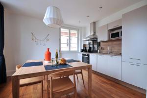 uma cozinha com armários brancos e uma mesa de madeira em Au Grenier à Sel Colmar em Colmar