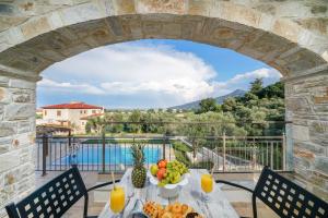 a table with fruit and juice on a balcony with a view at Mon Avis boutique hotel in Chrysi Ammoudia