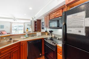 a kitchen with wooden cabinets and a black refrigerator at Driftwood Villa - 280 in Edisto Beach