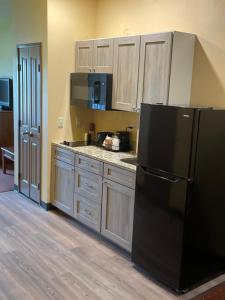 a kitchen with a black refrigerator and wooden cabinets at AmericInn by Wyndham Fargo Medical Center in Fargo