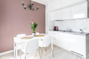 a white kitchen with a white table and white chairs at Apartament "Anna" - Kwartał Róży Wiatrów, 15 min spacerem od plaży in Świnoujście