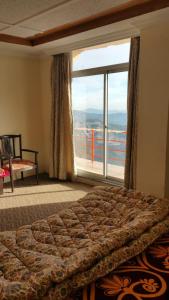 Un dormitorio con una cama y una ventana grande. en Peak Point Hotel & Apartments, en Murree