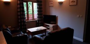 a living room with two leather chairs and a tv at Walnut Lodge, Summerhayes in Bridgwater