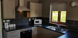 a kitchen with white cabinets and a black counter top at Walnut Lodge, Summerhayes in Bridgwater