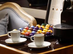 zwei Kaffeetassen und ein Tablett mit bunten Perlen auf dem Schreibtisch in der Unterkunft Mario De' Fiori 37 in Rom