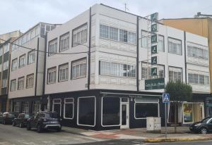 een hoog wit gebouw met auto's geparkeerd voor het bij La casa de la abuela in Narón