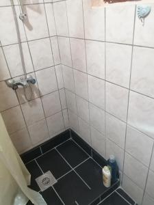 een douche met een zwarte vloer en witte tegels bij Gaga in Veliko Gradište