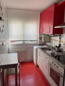 uma cozinha com armários vermelhos e um piso vermelho em Coqueto apartamento cerca de la playa em Santander