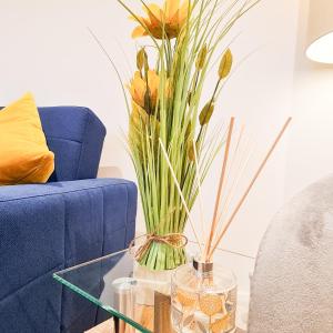 um sofá azul e uma mesa de vidro com um vaso com flores em Modern 4 bedroom flat near Brighton Station em Brighton & Hove