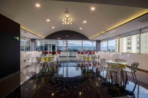 a dining room with white tables and chairs and windows at Luma Plaza Hotel in Pereira
